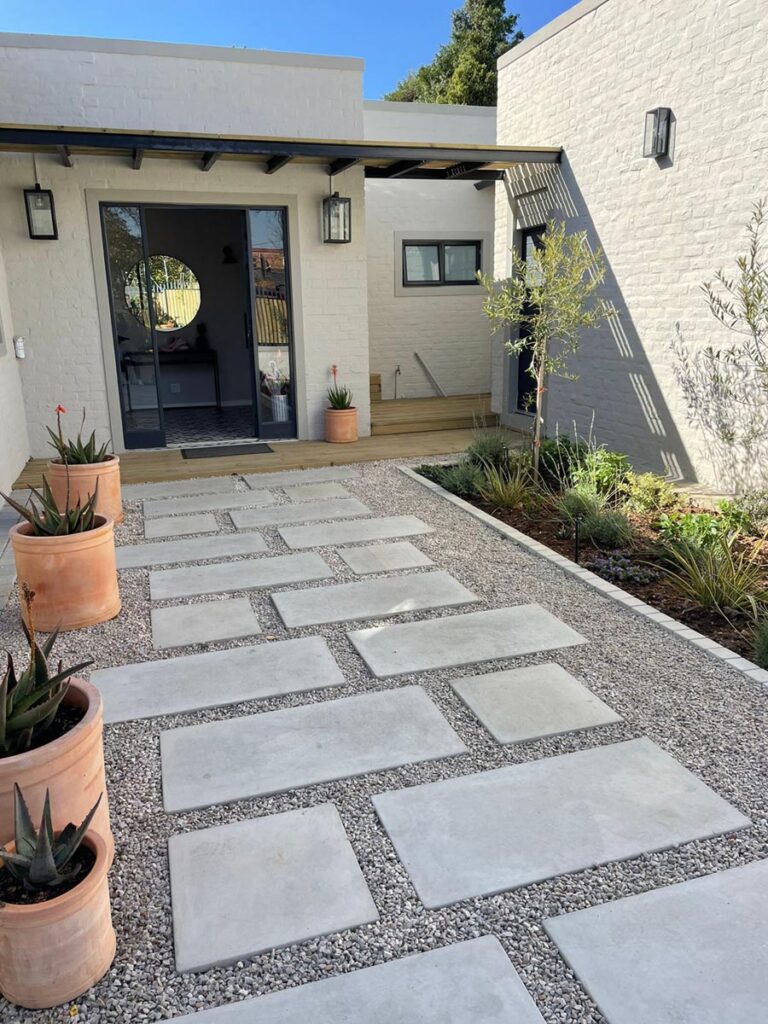 Square and rectangular concrete stepping stones entrance with small stones