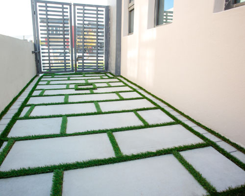 Rectangular Flagstones with artificial grass in-between creating an unique walkway
