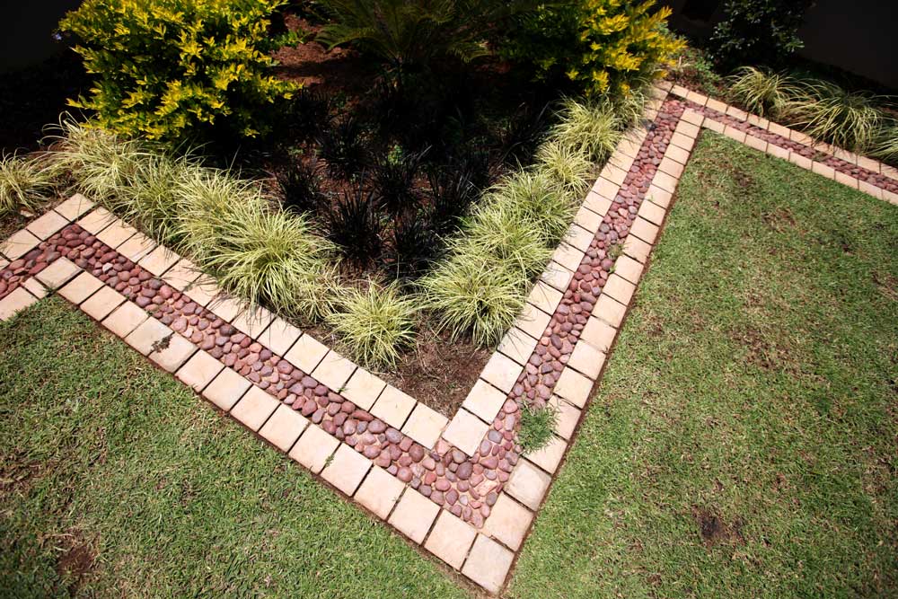 Double border garden edging with pebble stones bordered by light cobbles.