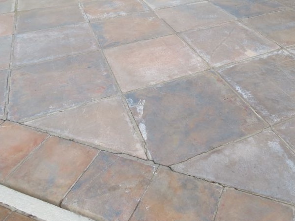 Paving failure due to cement grouting being used during installation.